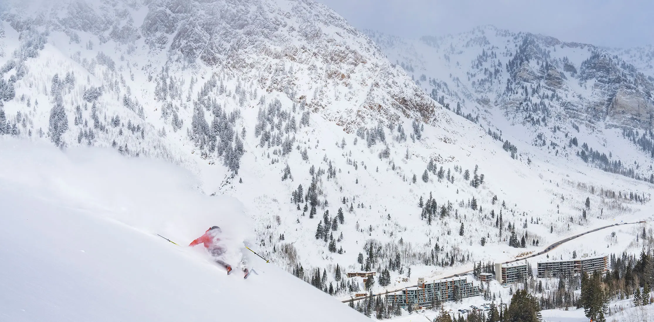 skier in powder with the Snowbird village and lodges in the background