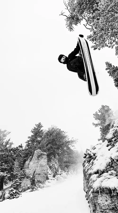 mobile hero- snowboarder jumping off a cliff in black and white