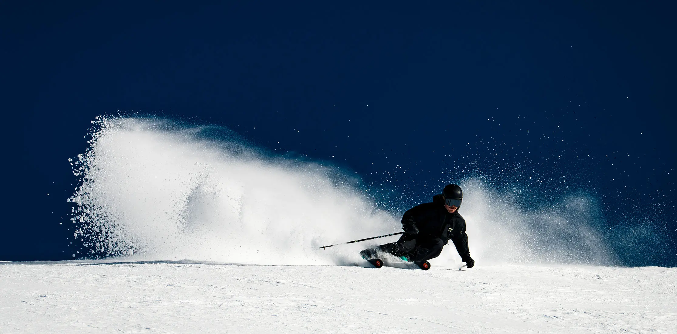 Skiing at Snowbird on a bluebird day with a cloud of snow behind him during the February Scan Challenge