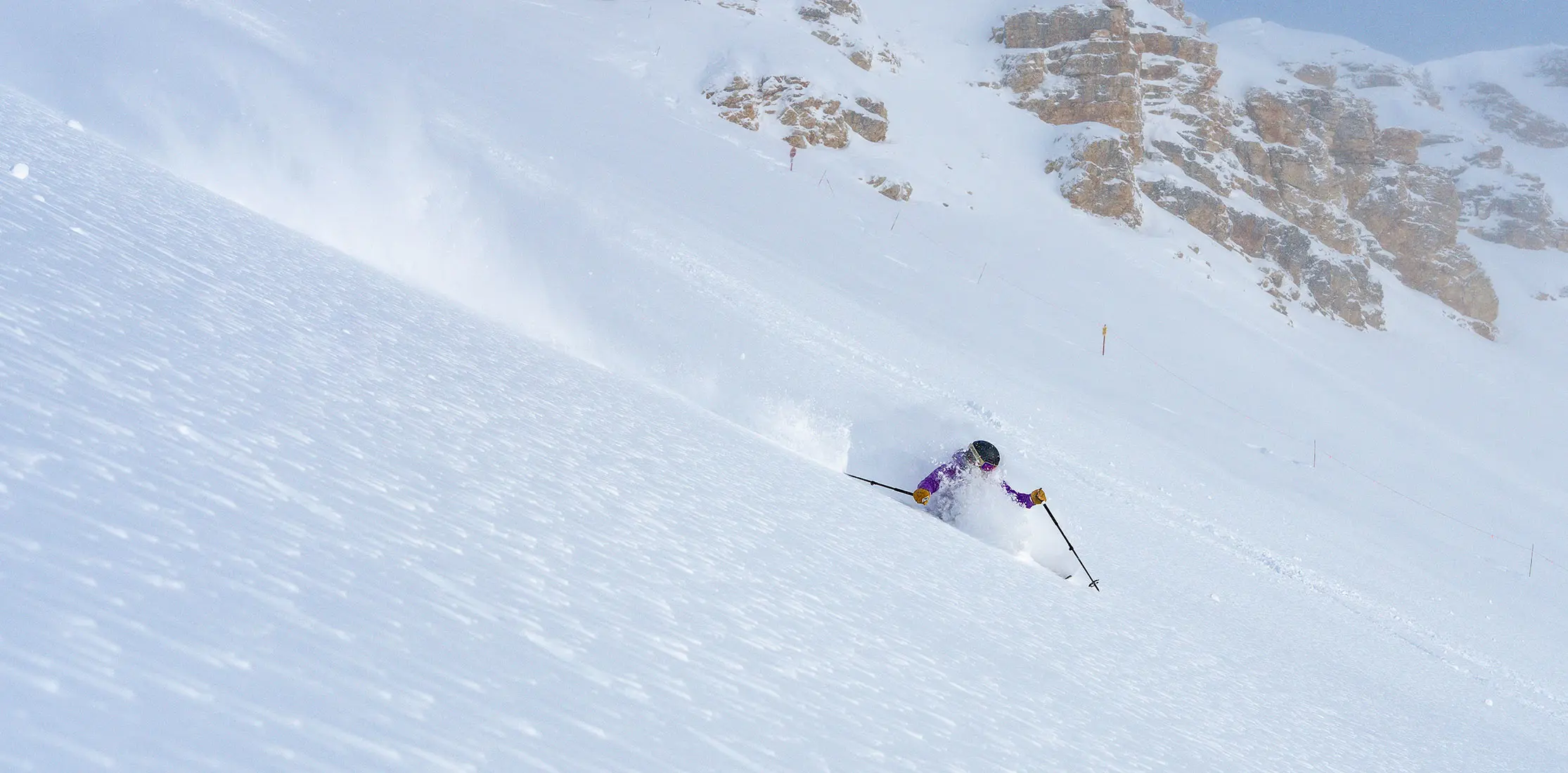 Skier in front of cliffs on a powder day in Mineral Basin
