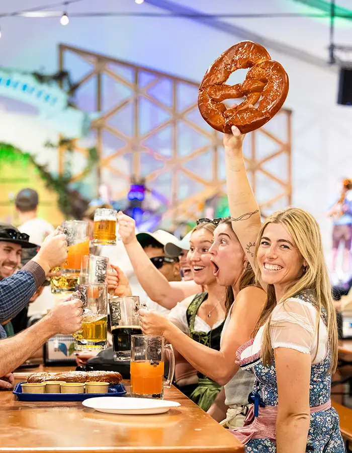 Mobile hero of girl at Oktoberfest holding up a pretzel