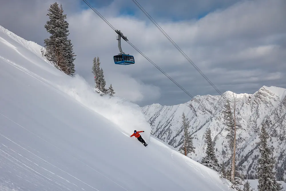 Snowboarder under the Tram at Snowbird with Little Cottonwood Canyon in the background